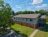 Charming two-story apartment building with brick and siding, nestled in a lush green setting under a clear blue sky.