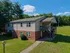 Charming two-story apartment building with earthy brick and sleek siding, surrounded by lush greenery and inviting outdoor seating.