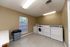 Bright and practical laundry room equipped with modern washers and dryers, featuring a large window allowing natural light.