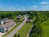 Aerial view of a serene neighborhood featuring modern homes, lush greenery, and clear blue skies, offering an inviting suburban ambiance.