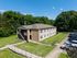 Charming two-story apartment building surrounded by lush greenery with ample parking space and inviting pathways, perfect for modern living.