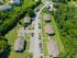 Aerial view of a charming residential community with spacious green lawns and well-maintained pathways surrounded by lush trees.