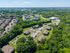 Aerial view of a serene residential area surrounded by lush greenery, showcasing spacious apartments and ample parking.