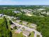 Aerial view of a serene apartment complex surrounded by lush greenery and convenient nearby amenities, offering a peaceful residential environment.