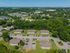 Aerial view of a charming apartment complex surrounded by lush greenery and situated in a serene neighborhood with ample parking and easy access to nearby amenities.