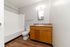 Bright, modern bathroom featuring sleek wood flooring, a spacious vanity with mirror, and a pristine white bathtub.