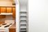 Modern kitchen corner featuring sleek wooden cabinets, a pristine white stove, and an efficient built-in shelving unit for convenient storage.