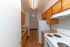 Charming galley kitchen with warm wooden cabinets, modern white appliances, and sleek countertops.