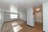 Bright living space with natural light, showcasing an open layout with hardwood floors and cozy carpeting, leading to a compact kitchen area.
