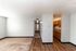 Bright and inviting apartment interior showcasing an open living space with elegant hardwood flooring and a cozy carpeted area, leading to a functional kitchen for modern living.