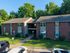 Charming brick apartment complex surrounded by lush green trees, offering a tranquil residential setting.