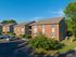 Charming suburban apartment complex with red brick exterior and lush green surroundings, perfect for family living.