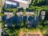 Aerial view of a charming residential complex surrounded by lush greenery, showcasing ample parking and well-maintained pathways.