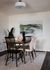 Chic dining area with a modern wooden table, stylish mixed chairs, and elegant decor, enhanced by a soothing abstract landscape painting.