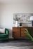 Elegant living space featuring a plush green sofa, chic wooden sideboard with decor, and contemporary art on the wall.