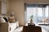 Chic living room with elegant decor, cozy seating, and a sunlit balcony view, perfect for relaxation.