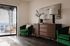 Chic living room with modern decor, featuring elegant green armchairs, stylish wood cabinet, and a balcony with stunning views.