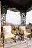 Charming balcony with elegant wrought iron details, featuring cozy wooden chairs overlooking a scenic view.