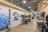 Inviting sports shop interior showcasing vibrant kayaks and paddleboards on wooden racks, with adventure-themed posters lining the industrial-style walls.