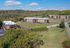 Aerial view of a charming apartment complex nestled in lush greenery with ample parking and scenic surroundings.