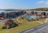 Charming apartment complex with scenic views of a lake, featuring a sparkling central pool, cozy gazebo, and lush greenery. Ideal for those seeking a peaceful and picturesque living environment.