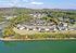Scenic aerial view of a charming apartment complex set amidst lush greenery, overlooking a serene body of water with vibrant autumn foliage.