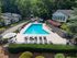 Inviting outdoor pool area surrounded by lush greenery and modern lounge chairs, offering a serene relaxation spot for residents.