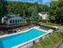 Inviting outdoor swimming pool with sun loungers surrounded by lush greenery and charming residential buildings.