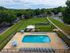 Charming outdoor view featuring a sparkling swimming pool with surrounding lounge chairs, a cozy gazebo, lush green lawn, and a children's playground, ideal for relaxation and recreation.