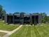 Contemporary apartment complex with sleek black facade, expansive windows, and lush green surroundings, offering a modern living experience.