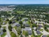 Aerial view of a lush residential neighborhood featuring modern apartment complexes, ample greenery, and winding roads under a clear blue sky.