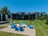 Modern apartment building with lush green lawns and a welcoming outdoor seating area with vibrant blue chairs around a cozy fire pit.