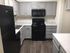 Modern kitchen with sleek gray cabinetry, black appliances, and elegant wood flooring.