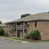 Charming brick apartment complex with lush greenery and inviting balconies, perfect for serene living.