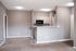 Inviting open-concept living area with plush carpeting and modern kitchen featuring sleek cabinetry and appliances.