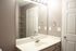 Bright and modern bathroom with a large mirror, sleek vanity, and ample shelving space, perfect for organizing essentials.