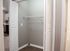 Spacious apartment closet with modern gray walls, sleek shelving, and a glimpse of adjacent kitchen area.