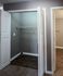 Spacious walk-in closet with sleek wood flooring and modern design, adjacent to a bright hallway.
