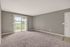 Bright and spacious living room with plush carpet, large sliding glass doors, and a scenic balcony view.