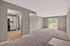 Inviting open-plan living space with modern kitchen, expansive carpeted area, and bright sliding glass door leading to a balcony with lush views.