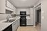 Modern kitchen with sleek white cabinetry, black appliances, and a dual sink, offering a contemporary and functional cooking space.