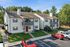 Charming two-story apartment complex with spacious balconies, nestled in a serene green setting with ample parking space.