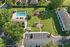 Picturesque aerial view of community amenities featuring a sparkling pool, modern playground, lush green spaces, and a convenient parking area.