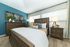 Inviting bedroom with elegant wooden furnishings, vibrant accent wall, and cozy decor creating a serene retreat.