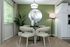 Cozy dining nook with elegant beige chairs and round mirror, accentuated by a lush green wall and soft natural lighting.