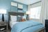 Inviting bedroom with soothing blue tones, elegant decor, and ample natural light through large windows.