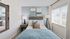 Inviting bedroom featuring a cozy bed with elegant cushions, soft lighting from floor lamps, and a large window allowing natural light to fill the room.