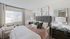 Charming bedroom with plush gray headboard, stylish wall art, and large window offering natural light and serene ambiance.
