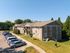 Charming apartment complex with ample parking, lush green surroundings, and stylish two-story design.