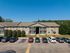 Charming apartment complex with manicured landscaping and ample parking, set against a lush green backdrop.